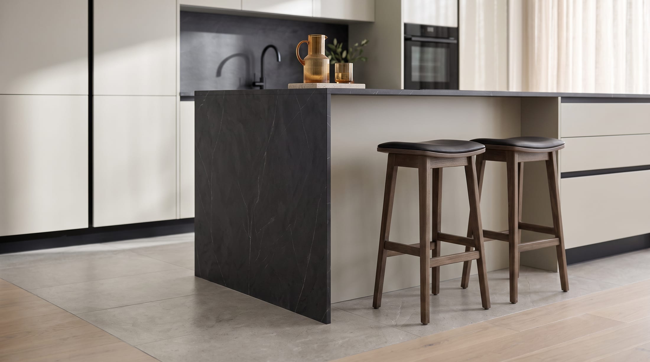 Gacaferi 1957 Sahara custom kitchen — black island with a waterfall edge and oak stools